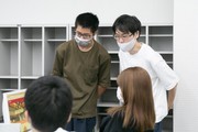 パソコンの前で4人の学生が話し合っている様子