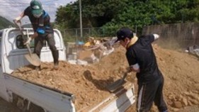 トラックの荷台から土をスコップでおろしている画像