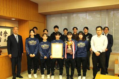 理事長と学長と男女バレー部の集合写真